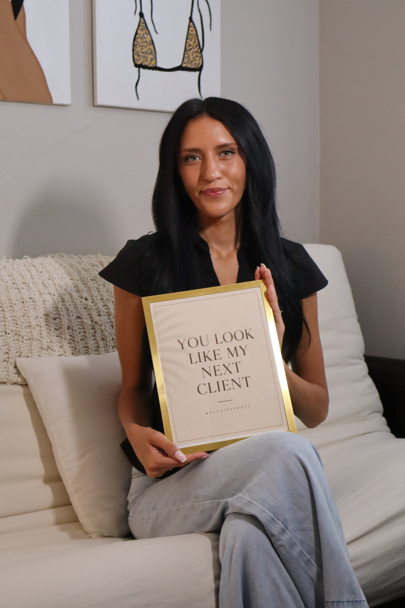Business owner holding a framed sign at her studio