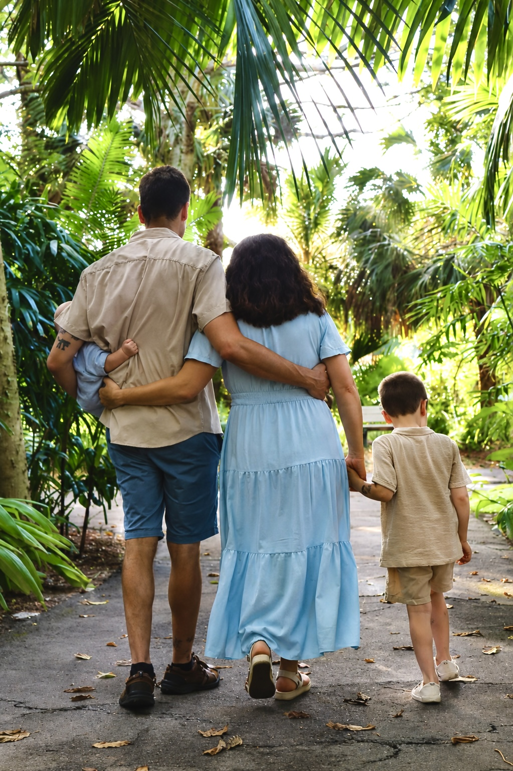 Family walking together along a palm-lined path